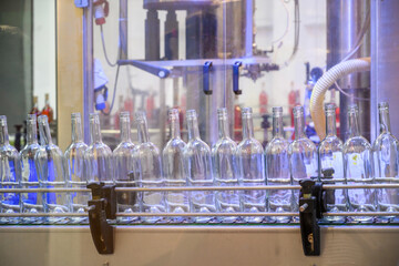 Glass empty bottles on the automatic conveyor line at the wine factory. Winery. Plant for bottling alcoholic beverages. Industrial production line unmanned operation cork sealing
