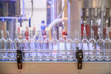 Glass empty bottles on the automatic conveyor line at the wine factory. Winery. Plant for bottling alcoholic beverages. Industrial production line unmanned operation cork sealing