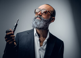 Portrait of elegant senior man dressed in suit and sunglasses smoking vape.