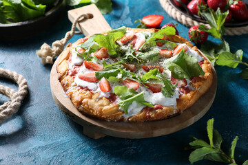 Summer season. Pizza with cheese strachatella, strawberries, arugula and mint with spices on a bright turquoise background. Rustic. Top view. Background image, copy space