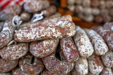 Stacks of dry-cured sausages - saucisson, typically made of pork, or a mixture of pork and other meats. Some variation contains spices and herbs, mushrooms, dried fruits, nuts, or cheese.