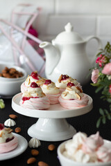 Black table spread with assorted meringues, white porcelain teapot, and pink roses in the background.