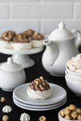 Dessert Pavlova with chocolate and hazelnuts. There is a dessert and white dishes on the table, a light background. Cream with mascarpone and whipped cream.