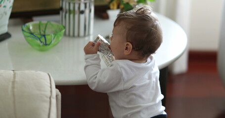 Baby standing up at home holding objects and falling down on floor