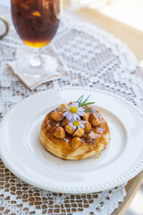 Homemade puff pastry deep fried donuts or cronuts in stack with sugar standing on white plate over table top with lace tablecloth. croissant and doughnut topping with macadamia nut and caramel sauce.