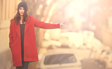 Stay well travelled in winter. Portrait of a gorgeous young woman in a red winter coat hailing a cab in the city.