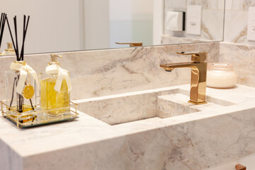 Luxurious bathroom decorated with marble stones. Bronze faucet detail.