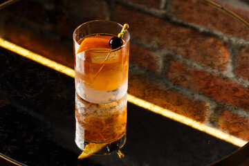 Crystal glass with bright cold alcoholic cocktail decorated with orange zest. Blurred background. Negroni cocktail.