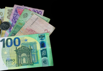 One hundred euro banknote and Ukrainian hryvnia close up on a black background with empty space