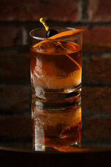 Crystal glass with bright cold alcoholic cocktail decorated with orange zest. Blurred background. Negroni cocktail.