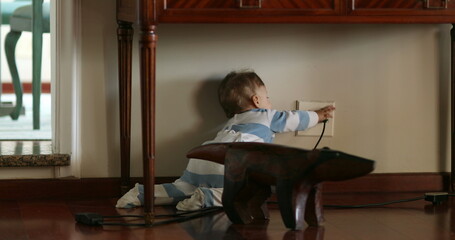 Baby infant on hardwood floor at home crawling and reaching to electrical outlet