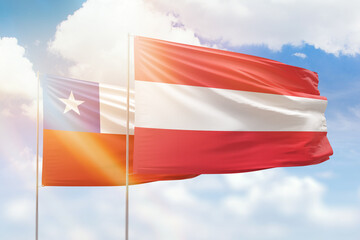 Sunny blue sky and flags of austria and chile