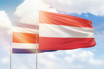 Sunny blue sky and flags of austria and costa rica