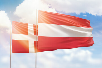 Sunny blue sky and flags of austria and denmark