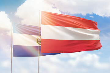 Sunny blue sky and flags of austria and el salvador
