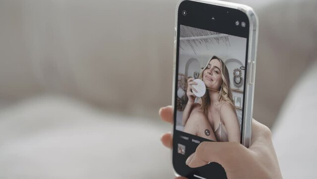 Close-up of beautiful young woman taking selfie. Action. Phone screen with selfie of young woman. Female blogger takes selfie with cosmetic product for advertising