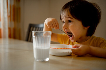 a child eats porridge for breakfast and drinks milk