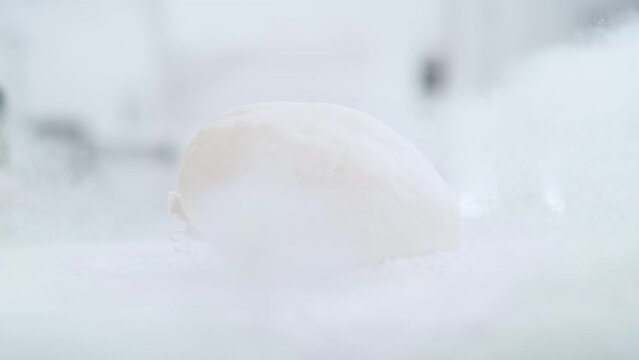 Kneaded Dough Ball Falling into Pile of Flour and Raising Up the White Powder in Slow Motion