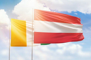 Sunny blue sky and flags of austria and ivory coast