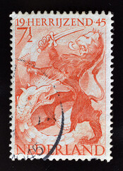 Cancelled postage stamp printed by Netherlands, that shows Dutch lion fighting the dragon, circa 1945.