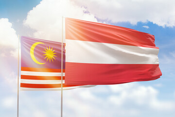 Sunny blue sky and flags of austria and malaysia