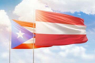 Sunny blue sky and flags of austria and puerto rico