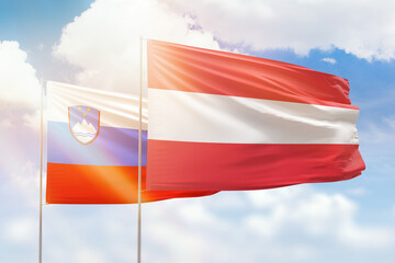 Sunny blue sky and flags of austria and slovenia