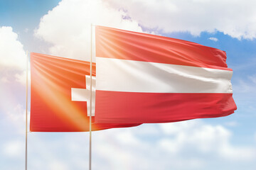 Sunny blue sky and flags of austria and switzerland