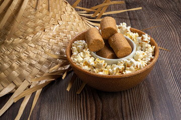 Popcorn, peanut candy served in a pot with straw hat on wooden background.