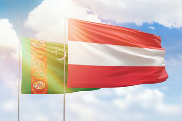 Sunny blue sky and flags of austria and turkmenistan