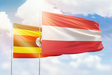 Sunny blue sky and flags of austria and uganda