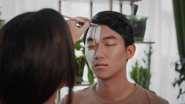 The stylist creates an image for an Asian guy for a photo shoot.