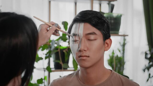The stylist creates an image for an Asian guy for a photo shoot.