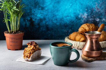 Brewed black coffee in a copper cezve. Coffee in mugs and sweets from nuts. Serving coffee.