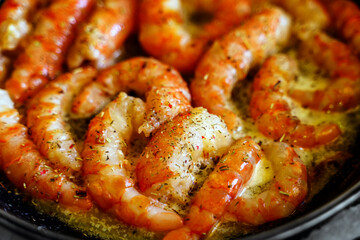 Large peeled shrimp are fried in butter in a frying pan