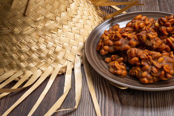 .Peanut candy served in a brown silver with straw hat on wooden background