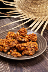 .Peanut candy served in a brown silver with straw hat on wooden background