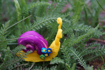 Snail figurine decorated with a flower on a background of green grass. Springtime.