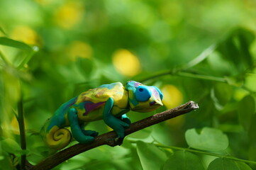 A toy colored chameleon on a tree branch. Animal figures.
