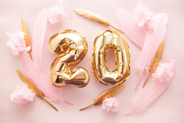 Happy twentieth birthday with golden number twenty 20 air balloons and feathers with colorful decorations on pink
