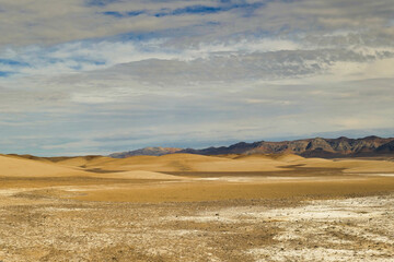 Abstract landscape of dunes and dark mountains in the desert and salt flats between Tecopa and the China Ranch Date Farm, California, Mojave Desert, Inyo County.
