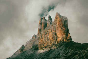 Back of the three peaks of Lavaredo that emerge from the clouds. Sesto Dolomites and Auronzo di Cadore Dolomites. Particular light - obrazy, fototapety, plakaty