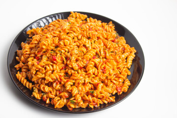 auger pasta on black plate on white background