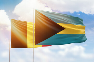 Sunny blue sky and flags of bahamas and belgium