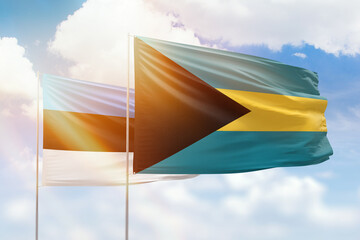 Sunny blue sky and flags of bahamas and estonia