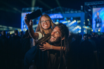 Couple taking selfie with a smartphone on a music festival