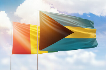 Sunny blue sky and flags of bahamas and guinea