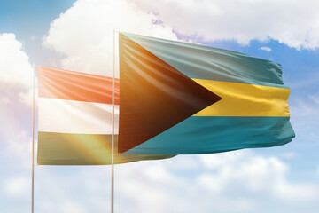 Sunny blue sky and flags of bahamas and hungary