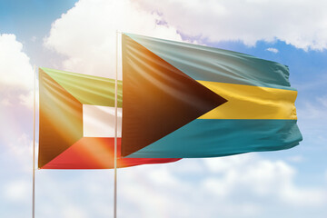 Sunny blue sky and flags of bahamas and kuwait