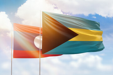 Sunny blue sky and flags of bahamas and laos